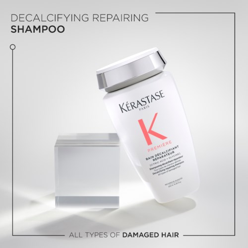 A shampoo bottle labeled 'Kérastase', with a white cap and simple design, aimed at damaged hair. Contains repairing and decalcifying benefits.