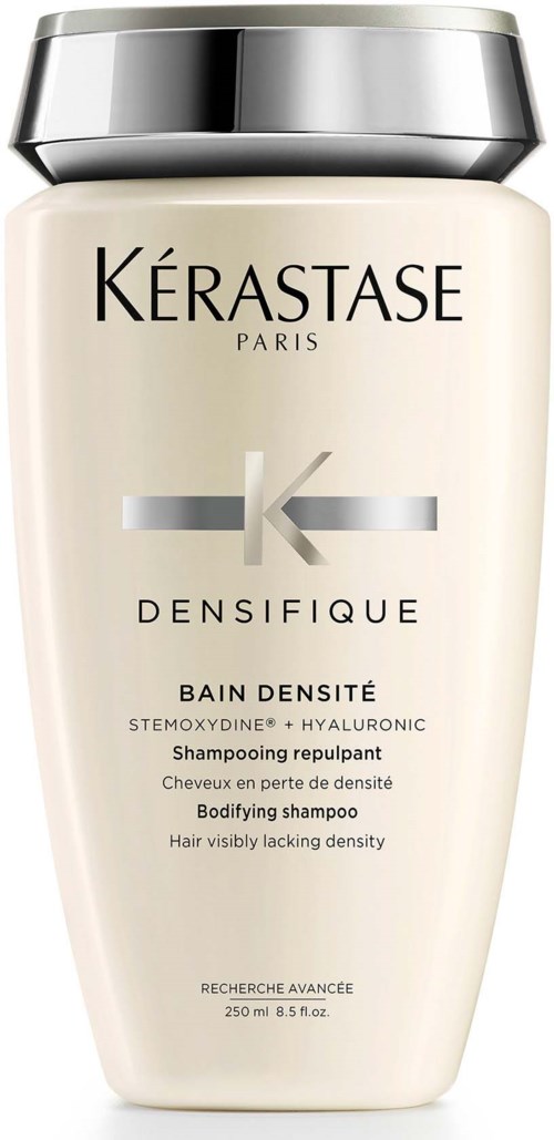 Een beige fles met zilveren dop, gemerkt 'Kérastase Densifique,' voor haarverdikking en volume.