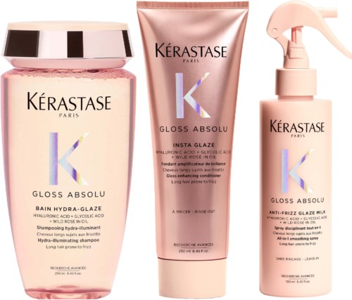 Drie Kérastase haarproducten in roze flessen: shampoo, conditioner en spray.
