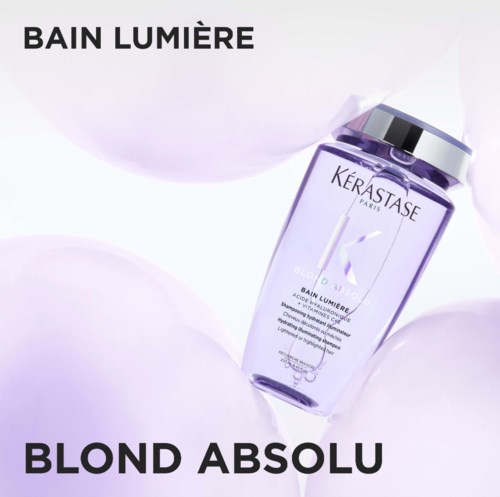 A purple bottle of Kérastase hair care product with text and a silver cap, surrounded by soft white background.