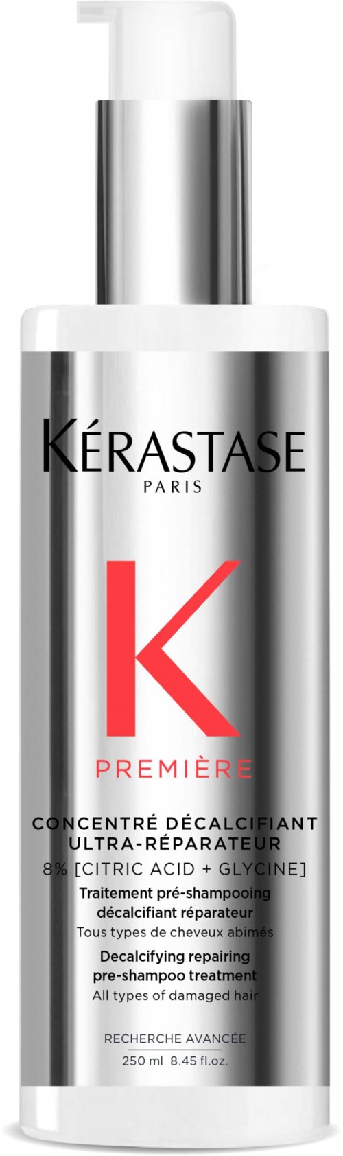 Een lange, zilveren fles met pomp, labelt Kérastase Paris, bevat een ontkalkende, herstellende haarbehandeling met rode en zwarte tekst.