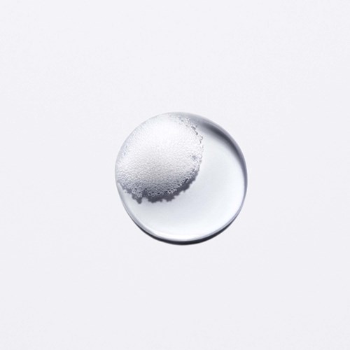En tydlig vätskebubbla med bubblor inuti, placerad på en enkel vit bakgrund.