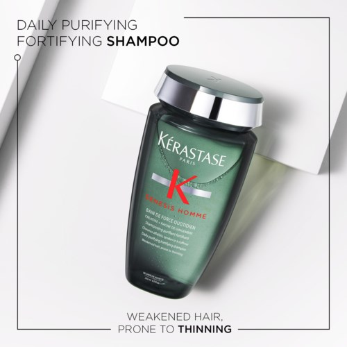 A green bottle of shampoo labeled Kérastase Paris, designed to strengthen hair and reduce thinning.