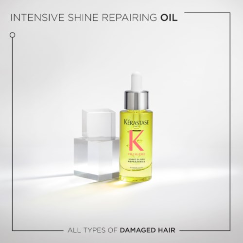 A yellow hair oil bottle called Kerastase, with a dropper, on a white background. It promotes repairing damaged hair.