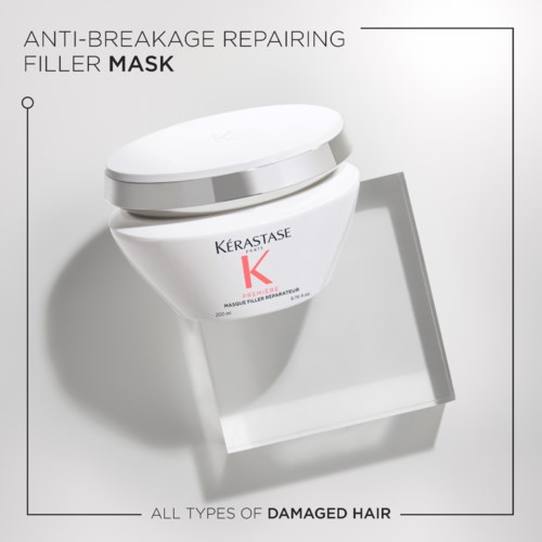 This is a white jar of hair mask for damaged hair, labeled Kerastase, with a silver lid, on a display stand.