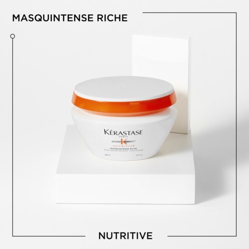 Een potje Kérastase haarmasker met oranje deksel op een witte standaard, met tekst: 'Masquintense Riche' en 'Nutritive.'