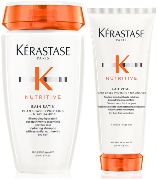 Twee Kérastase-haarproducten, één in een fles en één in een tube, beide met oranje doppen en accenten.