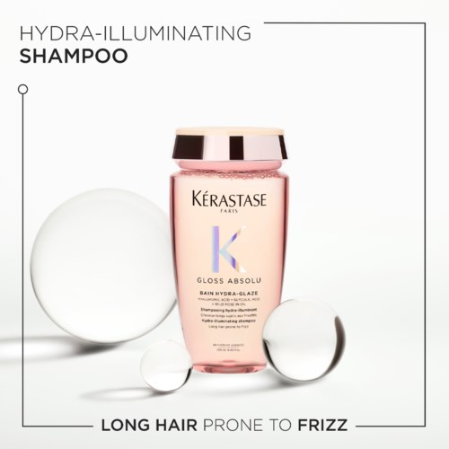 Kérastase shampoo bottle with pink liquid, surrounded by clear water droplets, on a white background.