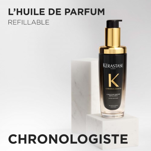 Een zwarte parfumfles met gouden dop en pomp, gelabeld Kérastase en Chronologiste, op een witte standaard.
