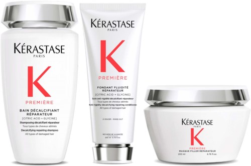 A line of three Kérastase hair care products including shampoo, conditioner, and mask, all with white packaging and silver caps.