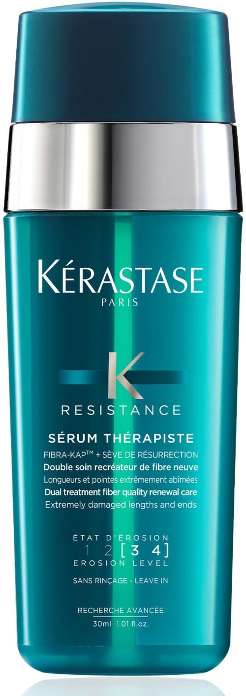 Een tealkleurige fles met zilveren dop bevat Kerastase Resistance serum voor beschadigd haar, gemarkeerd als een reconstructieve behandeling.