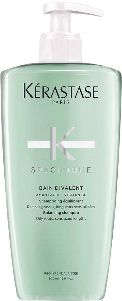 Een groene fles met witte pomp, gemarkeerd als Kérastase Specifique Balancing Shampoo voor vette wortels en gevoelige lengtes.