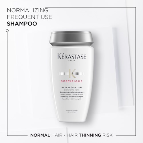 Een shampoefles met Kérastase-tekst over haarverzorging en preventie. Het is wit met een zilveren dop.