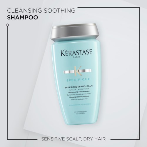 Een lichtblauwe fles Kérastase shampoo voor een gevoelige hoofdhuid en droog haar met een zilveren deksel.