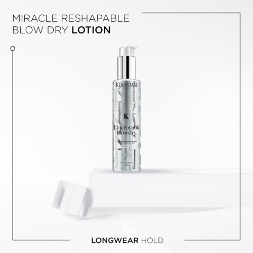 A clear bottle of blow dry lotion with a pump, labeled 'Kerastase', standing on a white surface with a cap nearby.