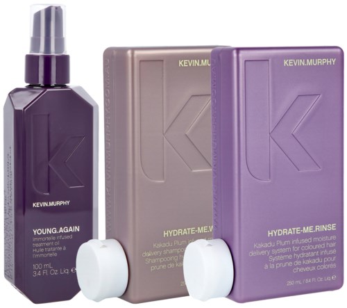 Drei Flaschen und Kartons in Lila und Grau, vermutlich Haar- oder Hautpflegeprodukte, mit der Marke Kevin Murphy.