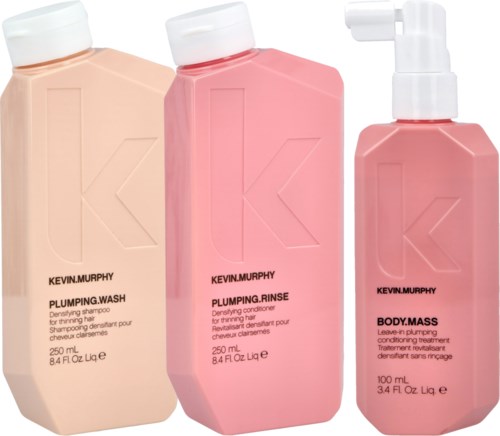 Three Kevin Murphy hair care bottles: shampoo, conditioner, and leave-in treatment, in peach and pink colors.