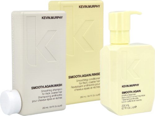 Three hair care bottles with minimalistic labels, one is a pump, all are in pastel yellow and white colors.