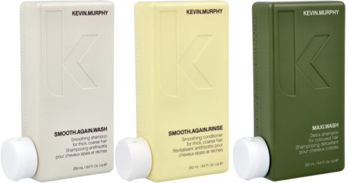 Three bottles of Kevin Murphy hair shampoo, conditioner, and wash in white, yellow, and green bottles.