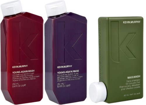 Three bottles of Kevin Murphy hair products, each a different color: red, purple, and green, with white caps.