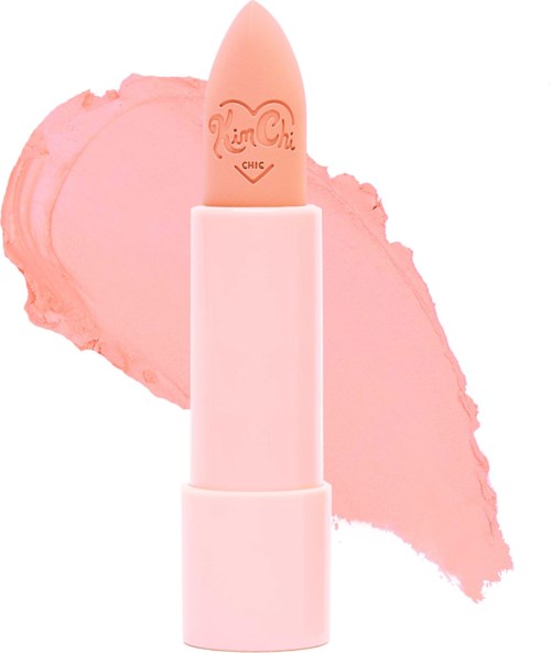 A pink lipstick with a light peach color, standing in front of a pink smudged background.