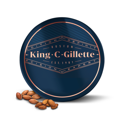 En rund blå burk med roséguldfärgad text och linjer, logo för King C. Gillette, med några nötter framför.