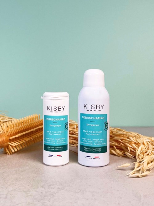 Two bottles of KISBY shower foam with wheat stalks on a light background.