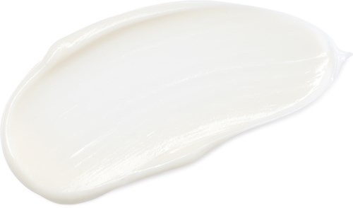 Witte crème of lotion uitgesmeerd op een zwarte achtergrond met een gebogen vorm.
