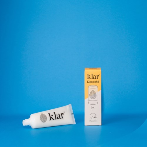 Een witte tube Klar Deo navulling en een gele doos met een spray-icoon op een blauwe achtergrond.