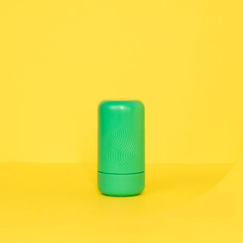 Een kleine groene deodorantstick met deksel, tegen een gele achtergrond.