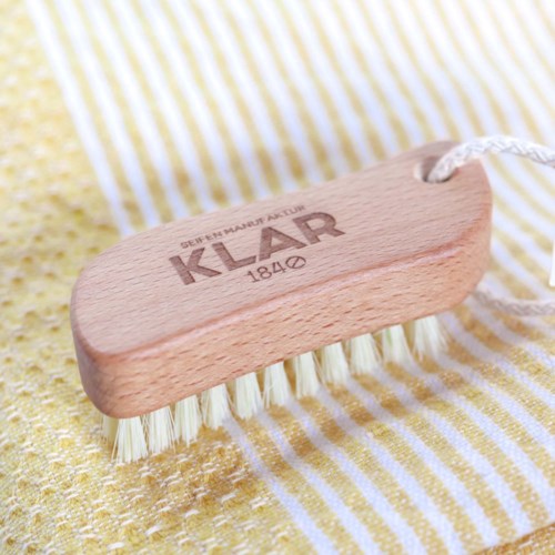 A wooden scrub brush with white bristles on yellow and white striped fabric.