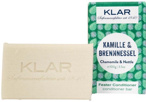 A soap bar labeled KLAR with creamy color, and a bright green box with white flowers and text, indicating it is a conditioner.