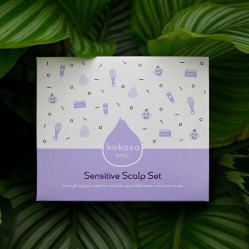 A box labeled 'Sensitive Scalp Set' with illustrations of hair care items, placed on leafy green plants.