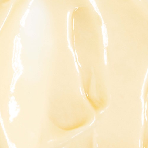 Nahaufnahme einer glatten, cremigen, gelblichen Oberfläche, möglicherweise Essen wie Käse oder Lotion.