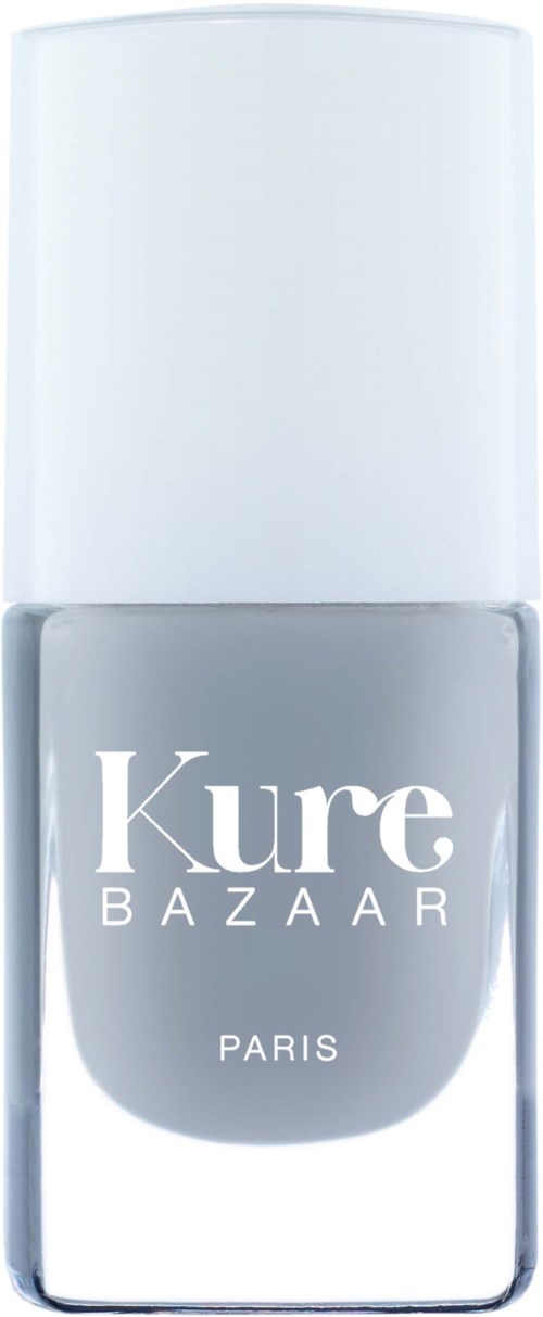 Ein Nagellackflasche mit weißem Deckel und grauem Etikett, auf dem 'Kure BAZAAR PARIS' steht.