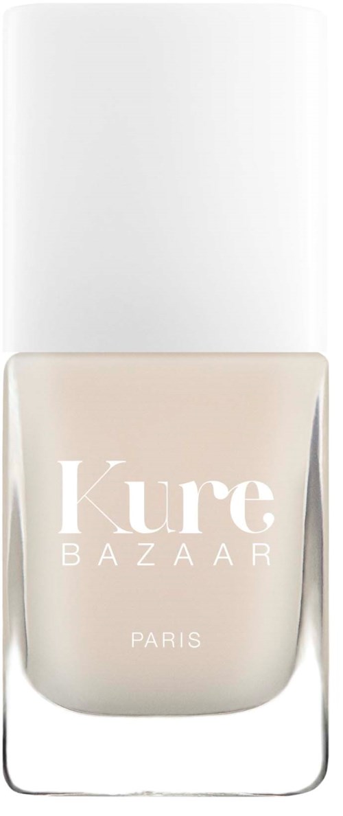 Eine klare Glasflasche mit weißem Deckel, beschriftet 'Kure BAZAAR PARIS' mit beigem Nagellack im Inneren.
