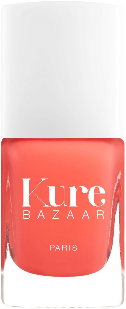 Ein korallenfarbener Nagellackflasche mit weißem Deckel, mit 'Kure BAZAAR PARIS' auf der Vorderseite.