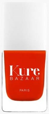 Eine hellorangefarbene Flasche mit den Worten 'Kure BAZAAR PARIS', vermutlich eine Kosmetik- oder Nagellackflasche.