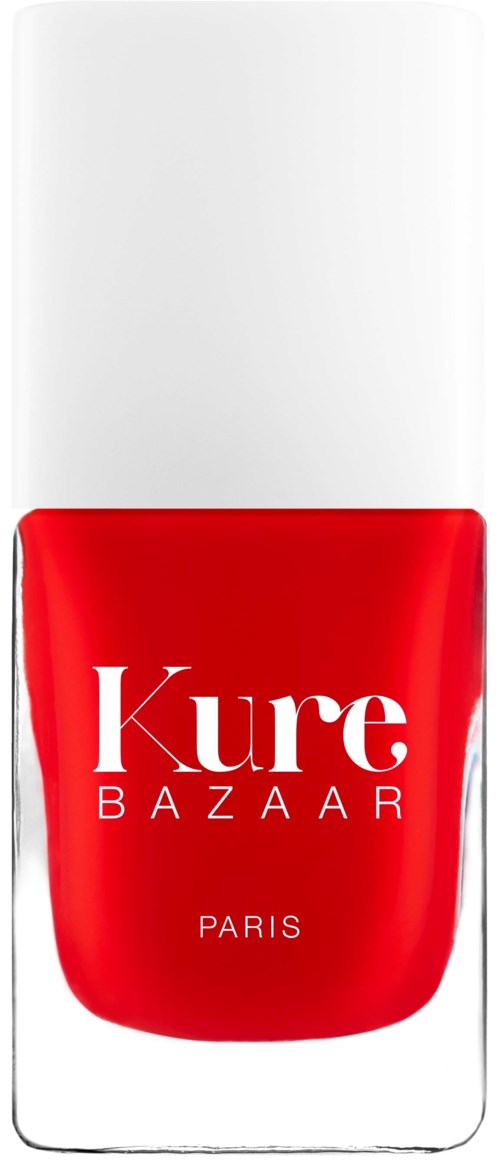 Eine rote Nagellackflasche mit weißen Text und langer weißer Kappe, beschriftet 'Kure BAZAAR PARIS.'