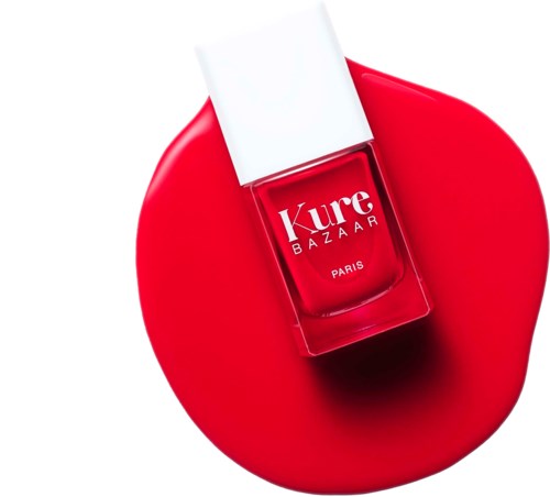 Rote Nagellackflasche auf roter runder Oberfläche mit weißem Deckel und Etikett "Kure Bazaar Paris."