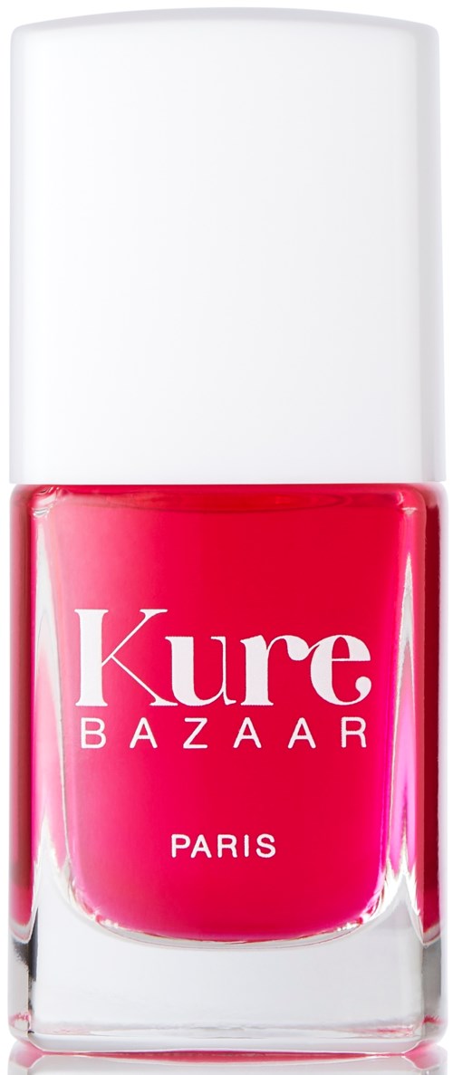 Eine hellrosa Nagellackflasche mit weißem Deckel und 'Kure BAZAAR PARIS' auf dem Etikett.