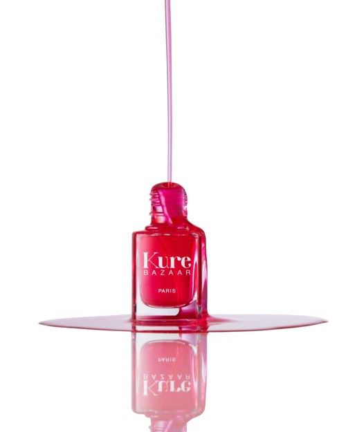 Rosa Nagellackflasche mit auslaufender Lack, reflektiert auf Oberfläche darunter.