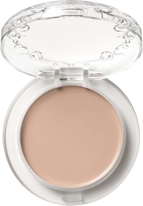 En liten dosa med beige makeup inuti, öppen med ett klart, dekorativt lock. Inga andra föremål synliga.