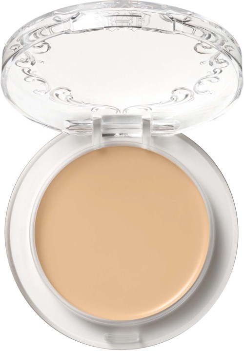 En liten dosa med rund, beige färgad yta och genomskinligt lock, används för makeup eller hudvård.