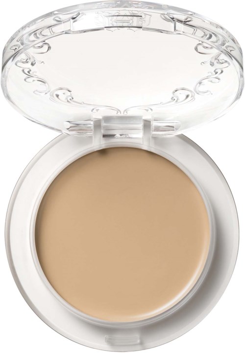 En liten vit behållare med ett transparent lock, som innehåller beigefärgad kräm eller concealer.