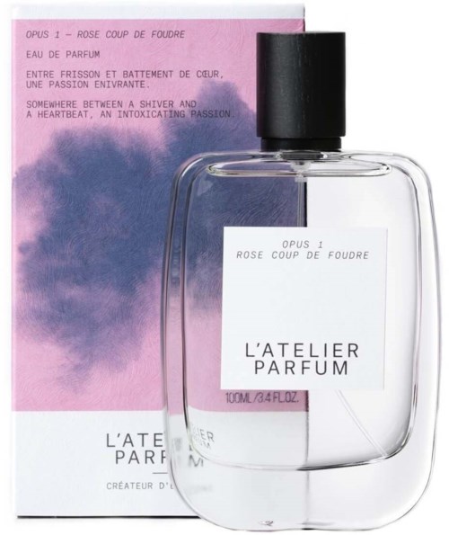 A perfume bottle with a pink and purple box, labeled 'L'Atelier Parfum' with additional text about fragrance notes.