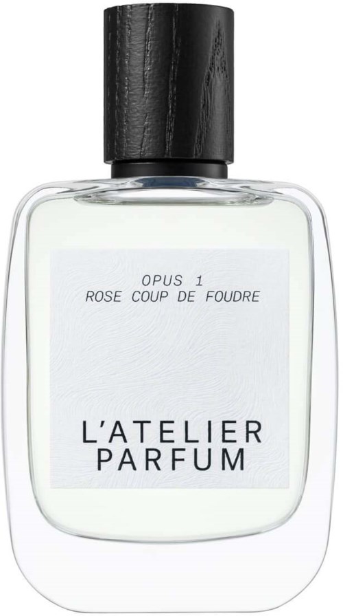A clear perfume bottle with a black cap, labeled "L'ATELIER PARFUM," contains fragrance called "ROSE COUP DE FOUDRE."
