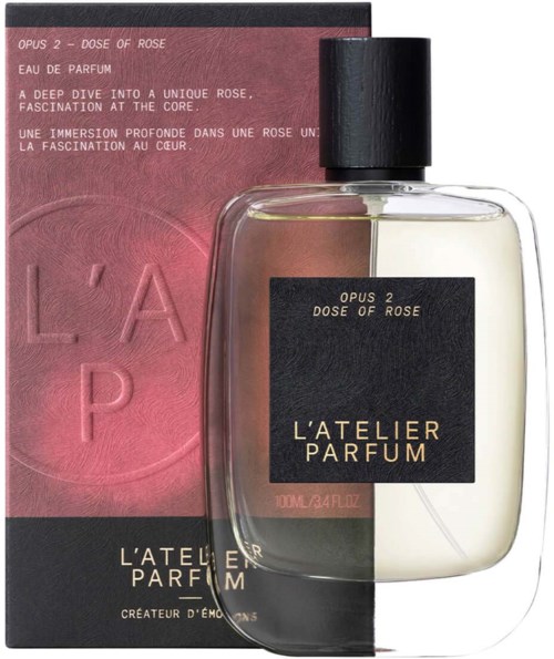 A perfume bottle with a black cap, beside pink and black packaging with product details.