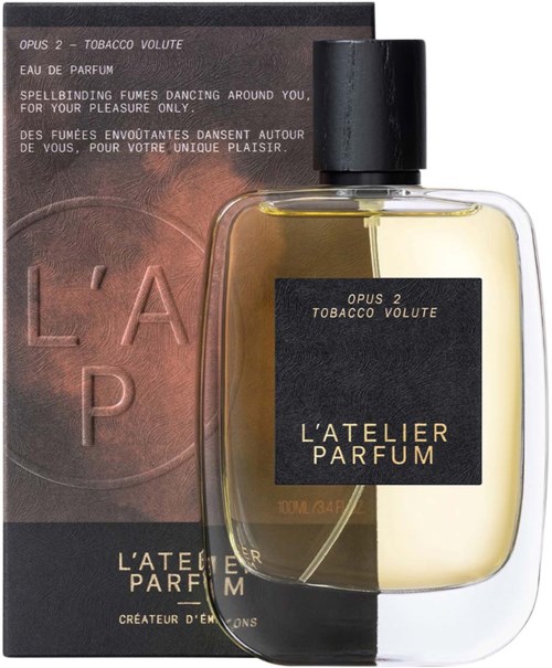 A perfume bottle with a black label and a box behind it. The label says "L'ATELIER PARFUM."