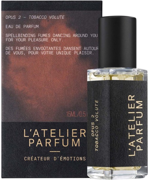 A perfume bottle and box named L'Atelier Parfum, with black and gold labels, and text describing its scent and mood.
